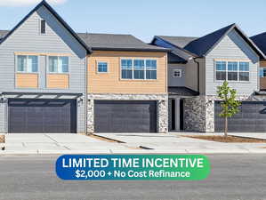 View of front of property with stone siding, concrete driveway, and a garage