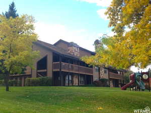 Rear view of property featuring a yard, a playground, a chimney, and stone siding
