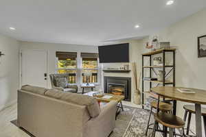 Living area featuring a fireplace with flush hearth, recessed lighting, and light wood-style flooring