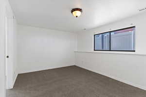 Empty room featuring dark carpet and baseboards