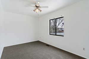 Unfurnished room featuring ceiling fan and dark carpet