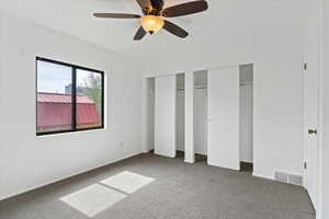 Unfurnished bedroom featuring two closets, carpet, and ceiling fan