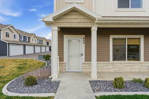 Doorway to property with a porch, board and batten siding, stone siding, and a residential view