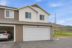 View of front facade featuring a shingled roof, a mountain view, board and batten siding, an attached garage, and driveway