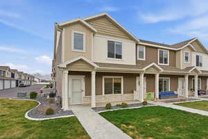 View of front facade with a front yard, roof with shingles, and stone siding