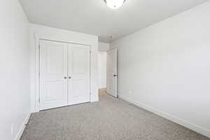 Unfurnished bedroom with light colored carpet and a closet