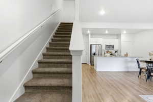 Stairs featuring wood finished floors and recessed lighting