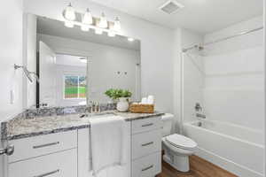 Bathroom with vanity, dark wood finished floors, and bathing tub / shower combination