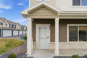 Entrance to property with a porch, stone siding, board and batten siding, and a residential view