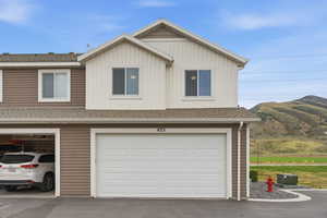 View of front facade with a shingled roof, an attached garage, board and batten siding, asphalt driveway, and a mountain view
