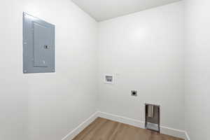 Laundry area with electric panel, light wood-style floors, hookup for a washing machine, and hookup for an electric dryer