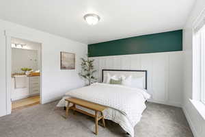 Bedroom featuring light colored carpet, a decorative wall, connected bathroom, and a wainscoted wall