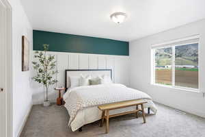 Carpeted bedroom featuring a decorative wall