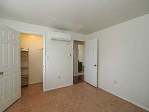 Unfurnished bedroom featuring a walk in closet and parquet floors