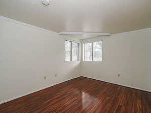 Unfurnished room with dark wood-style flooring, a smoke detector, and crown molding