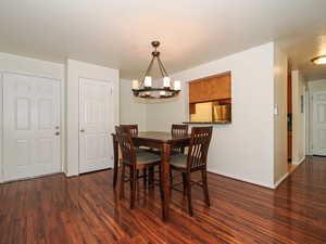 Dining area with hanging lights and dark wood-style flooring