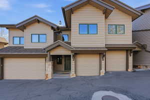 View of front of home featuring a shingled roof, stone siding, and a garage