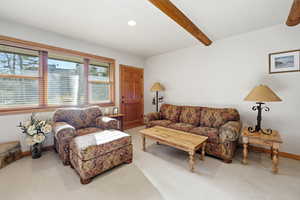 Carpeted living area with beamed ceiling and recessed lighting