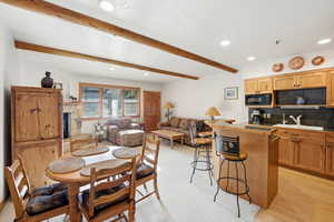 Kitchen featuring beam ceiling, open floor plan, backsplash, recessed lighting, and a fireplace