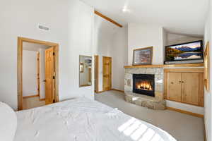 Bedroom featuring a fireplace, light carpet, and lofted ceiling