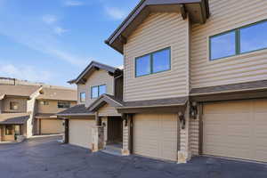 View of front of property with a shingled roof, an attached garage, and a residential view