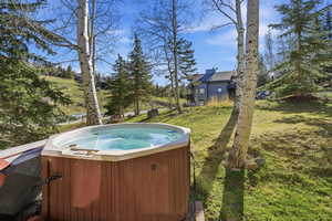View of pool with a hot tub and a lawn