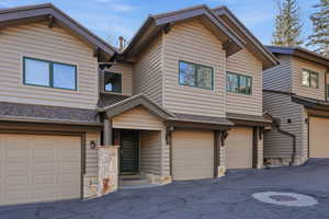 View of front of house with log veneer siding, a garage, and a shingled roof