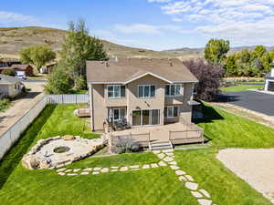 Rear view of property with a fire pit, roof with shingles, a lawn, a deck with mountain view, and stucco siding
