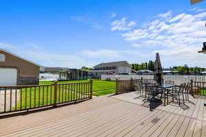 Wooden deck featuring a residential view, outdoor dining space, a fenced backyard, and an outdoor structure