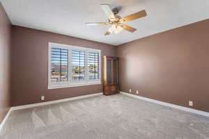 Unfurnished room featuring light carpet, ceiling fan, and a textured ceiling
