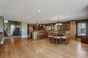 Dining space with light wood finished floors, hanging lights, and a textured ceiling