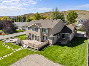 Rear view of house with a shingled roof, a deck with mountain view, a fire pit, and a fenced backyard