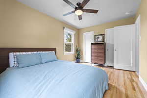 Bedroom with a ceiling fan, light wood-type flooring, and a textured ceiling