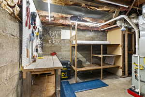 Unfinished basement with a workshop area and heating unit