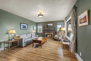 Living room with a fireplace, light wood-style flooring, and a textured ceiling