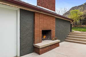View of patio featuring an outdoor brick fireplace and a mountain view