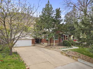 Obstructed view of property featuring brick siding, driveway, an attached garage, and a front lawn