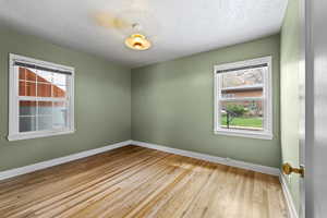 Spare room featuring light wood-type flooring and a textured ceiling