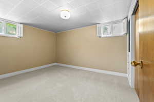 Below grade area featuring light carpet and baseboards