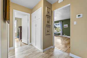 Hallway with light wood-style floors and a textured ceiling