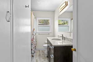 Bathroom featuring vanity, a textured ceiling, a shower with shower curtain, and light wood-style flooring