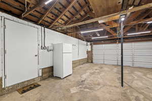 Garage featuring freestanding refrigerator and concrete block wall