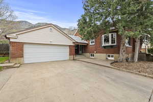 View of front of home with brick siding, concrete driveway, and an attached garage