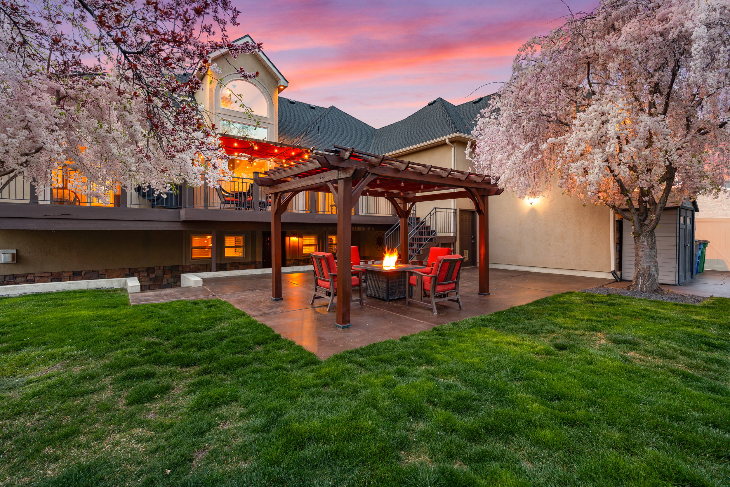 Rear view of property featuring a pergola, a yard, an outdoor fire pit, and stucco siding