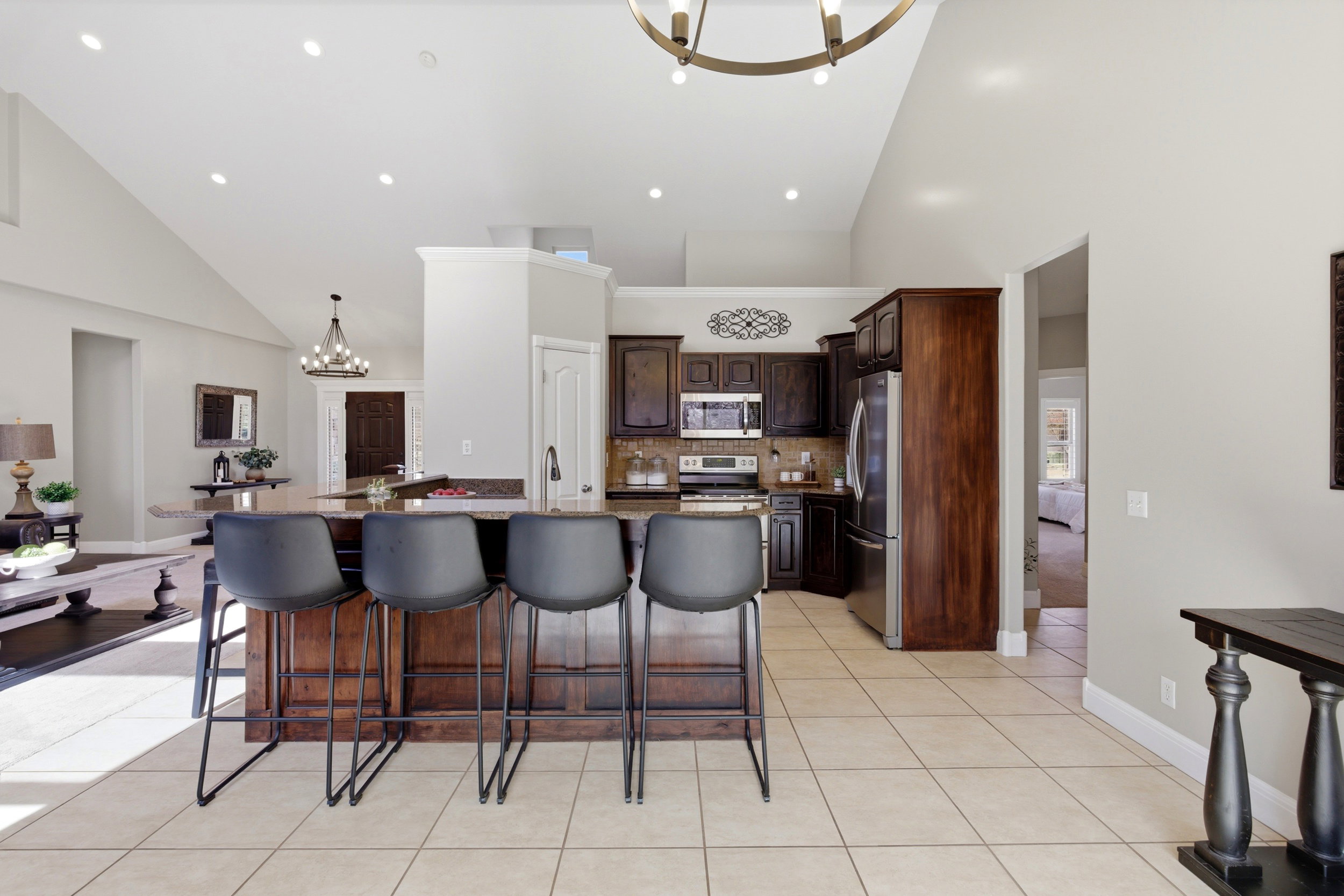 Kitchen featuring hanging lights, dark wood finish cabinetry, a kitchen breakfast bar, dark stone counters, and stainless steel appliances