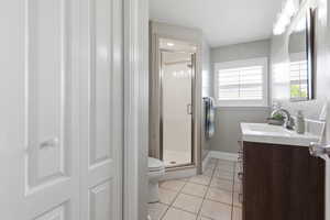 Full bathroom with vanity, light tile patterned floors, and a stall shower