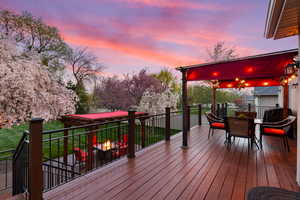 Deck at dusk with outdoor dining area and an outdoor fire pit