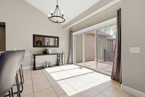 Unstaged dining area with lofted ceiling, suspended lighting, and light tile patterned floors