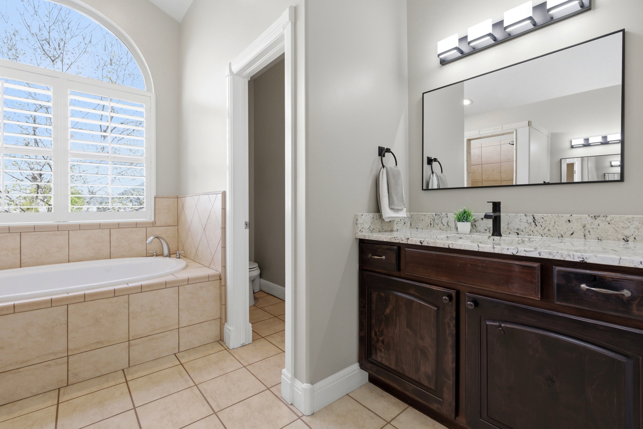 Bathroom with vanity, light tile patterned floors, and a garden tub