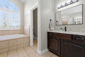 Bathroom with vanity, light tile patterned floors, and a garden tub